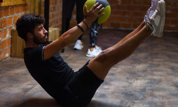 Focused man performing core exercises with a medicine ball in an indoor gym highlighting fitness and strength.